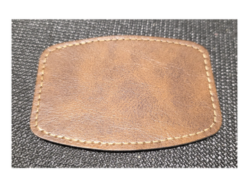Brown leather patch with stitching on a textured black surface.