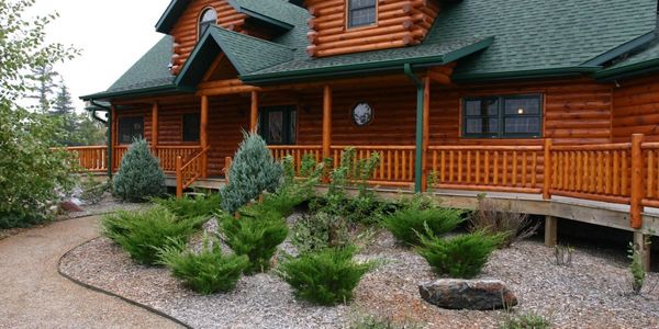 A cozy log cabin with green roof and landscaped garden pathway.