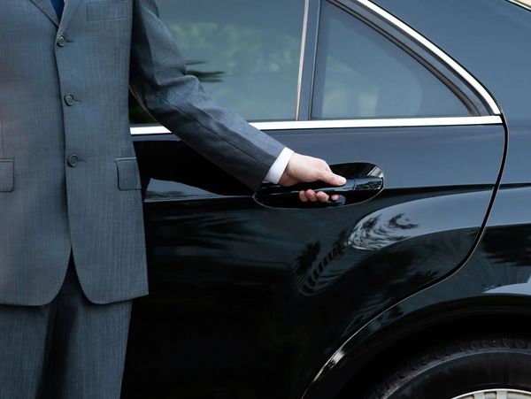 Chauffeur opening black luxury car door