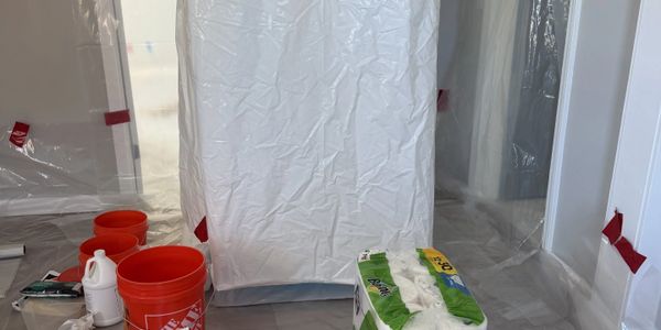 Room prepared for painting with plastic covers and supplies.