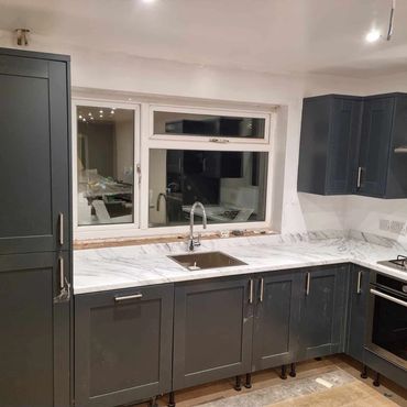 A navy kitchen with satin handles and kitchen appliances.