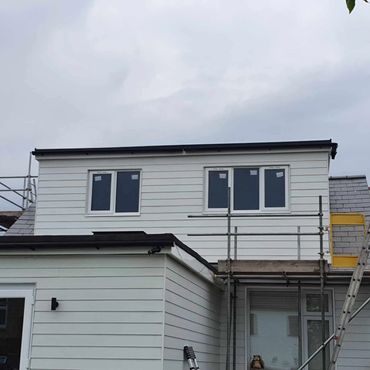A rear flat dormer loft conversion externally cladded in Hardie Plank cladding in white.