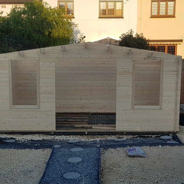 The construction of a log cabin in a back garden.