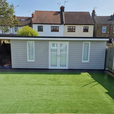 A custom built summerhouse with a flat roof and exterior cladding in grey.