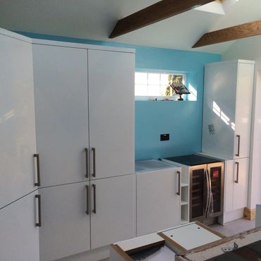 A white gloss kitchen fitted with stainless steel handles.