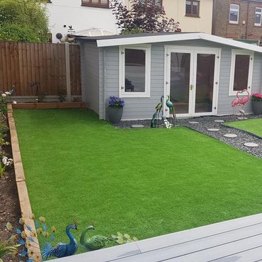 A bespoke log cabin in the back garden painted grey.