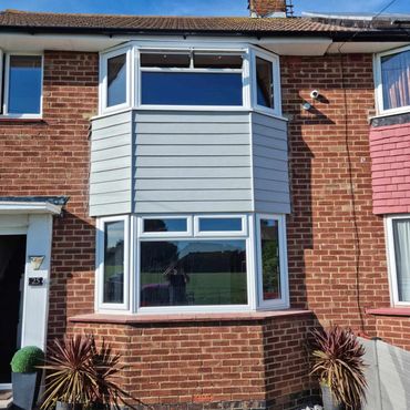 External cladding, replacing the tiles between the windows, on a two storey house.