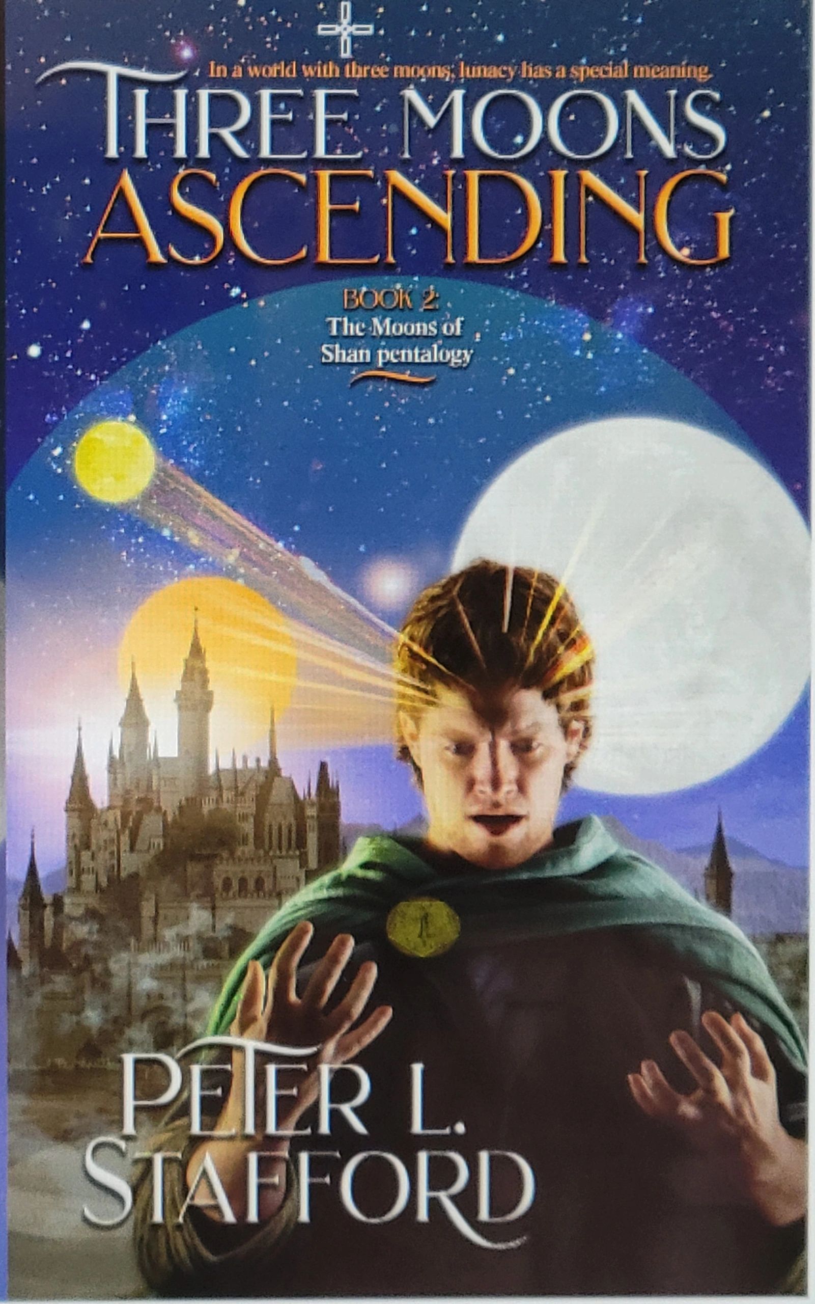 Fantasy book cover showing a young man with magical energy and three moons in the sky.