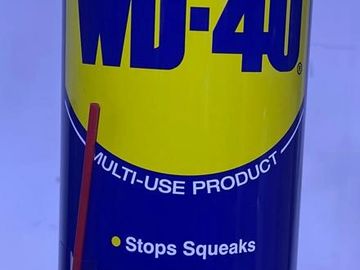 Close-up of a WD-40 multi-use product can with a red straw attached.