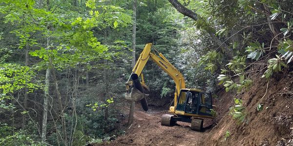 Shane Hamilton grading a mountain road with a large excavator in Poplar,NC.