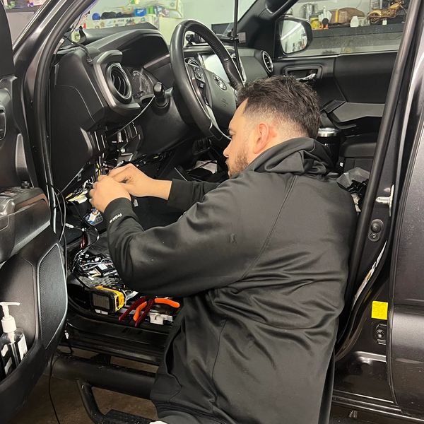 Man repairing a car's interior electronics.