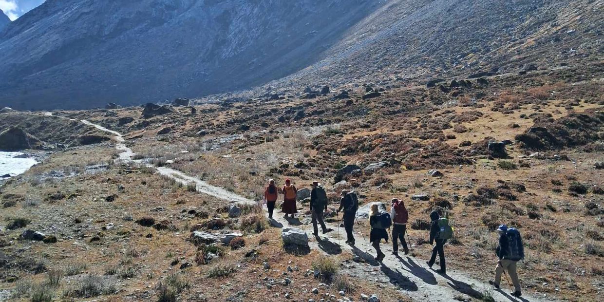 Group hiking on a mountain trail with backpacks and walking sticks.