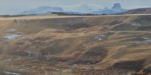 Snow-dusted mountains with rolling hills in the foreground.