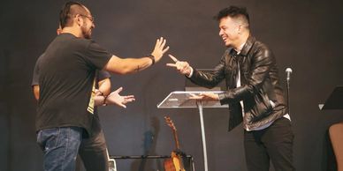 Two men enthusiastically playing rock-paper-scissors on stage.