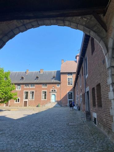 View of a historic cobblestone courtyard framed by a stone arch