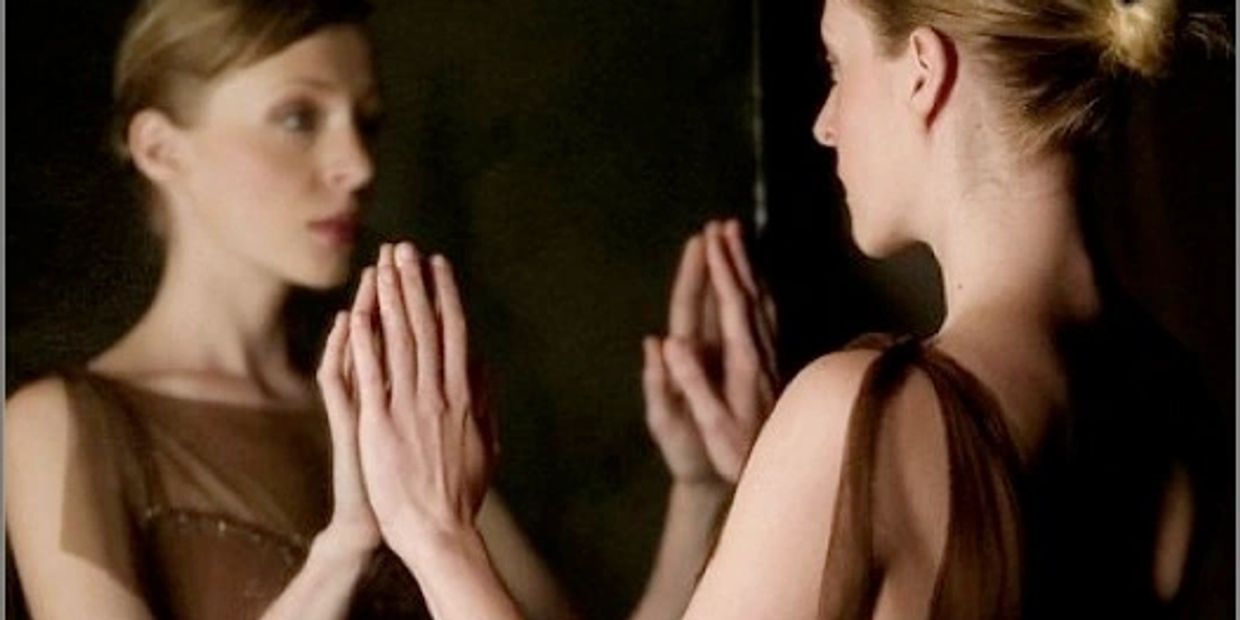Mirror image; woman sees herself in the mirror