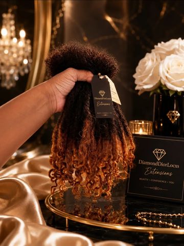 Hand holding curly ombre hair extensions with luxurious decor.