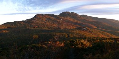 Mountain range bathed in warm sunlight under a partly cloudy sky.