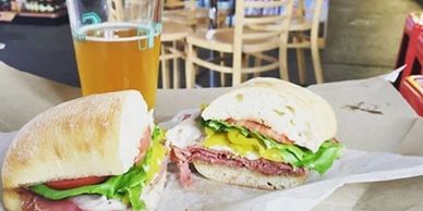 A fresh sandwich with lettuce, tomato, and meat paired with a glass of beer in a casual eatery.