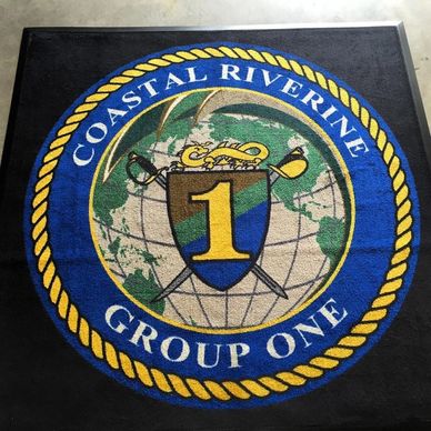 Emblem of Coastal Riverine Group One on a mat with blue, yellow, and green colors.