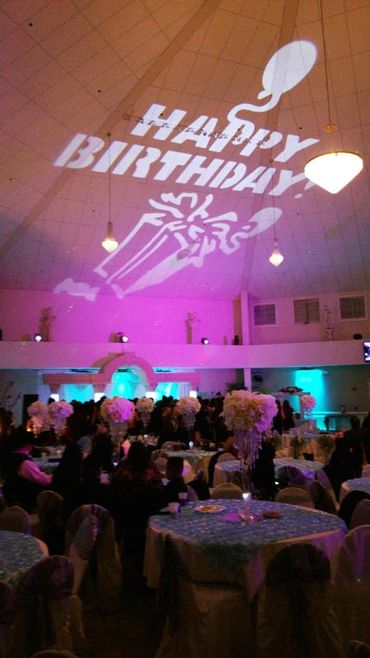 Birthday party with elegant decor and projected message on ceiling.