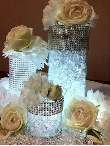 Elegant floral centerpiece with white roses and crystal decorations.