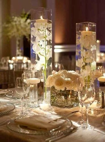 Elegant table setting with floating candles and white floral arrangements.