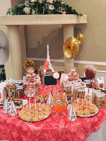 Paris-themed dessert table with Eiffel Tower decorations and assorted treats.