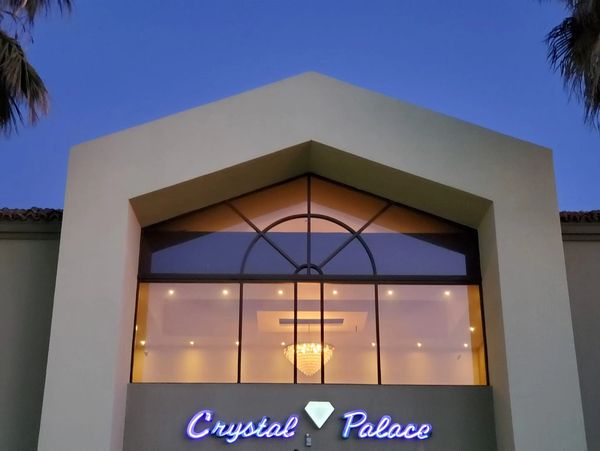 Elegant building entrance with illuminated 'Crystal Palace' sign and chandelier inside.
