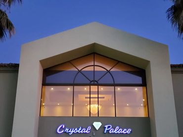 Elegant building entrance with illuminated 'Crystal Palace' sign and chandelier inside.