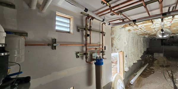 Copper plumbing pipes and water filter system installed in a basement.