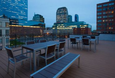Empty rooftop patio with tables and city skyline at dusk.