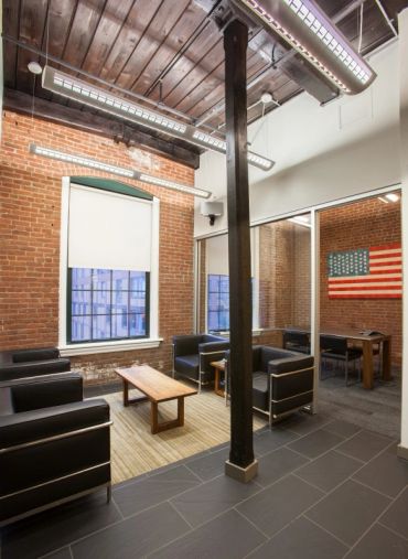 Modern office lounge with leather chairs and exposed brick walls.