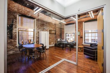 Modern office with exposed brick walls and glass partitions.