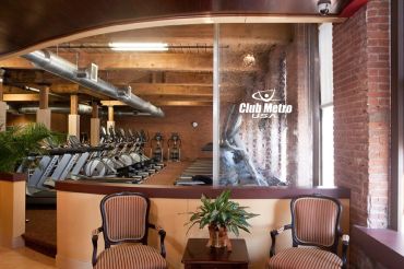 Cozy lounge area with chairs and plant inside Club Metro Fitness gym.