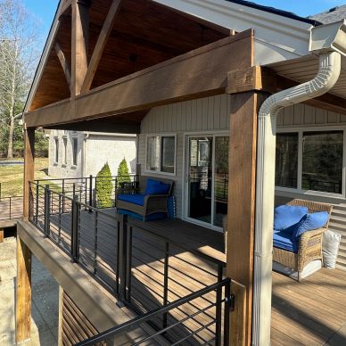 Cozy covered porch with wooden beams and blue cushioned chairs.