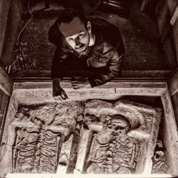 A person looking at the camera, sitting near a grave
