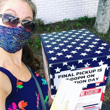 A woman wears a face mask and drops her ballot into a voter ballot box in Dekalb County, Georgia