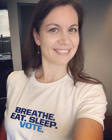 A woman wearing a t-shirt that says Breath. Eat. Sleep. Vote.
