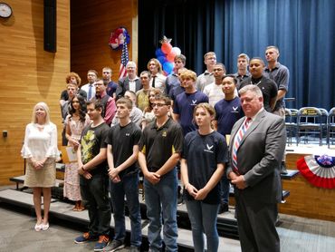 Group photo of young adults and officials at a patriotic event.