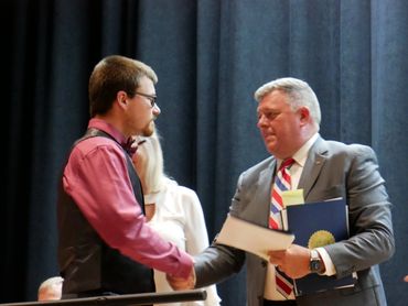 Two men shaking hands during an award ceremony on stage.