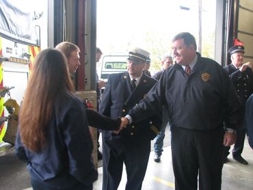Firefighters and officials shaking hands in a fire station.