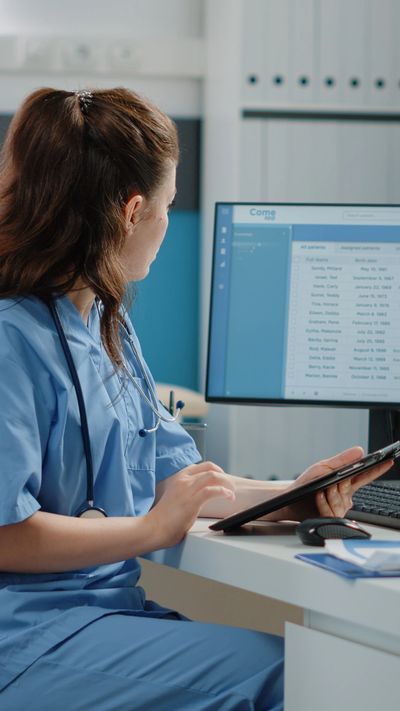 Medical assistant working with computer and digital tablet for healthcare system and appointments.