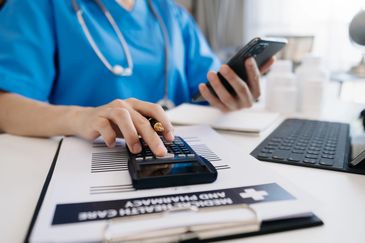 Hand of smart doctor used a calculator and smartphone, tablet for medical costs.