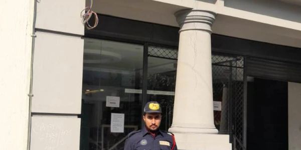 Security guard standing outside a building with columns.