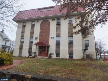 Three-story residential building with red roof and brick entrance.