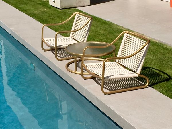 pair of white and gold midcentury modern patio chairs with matching table 