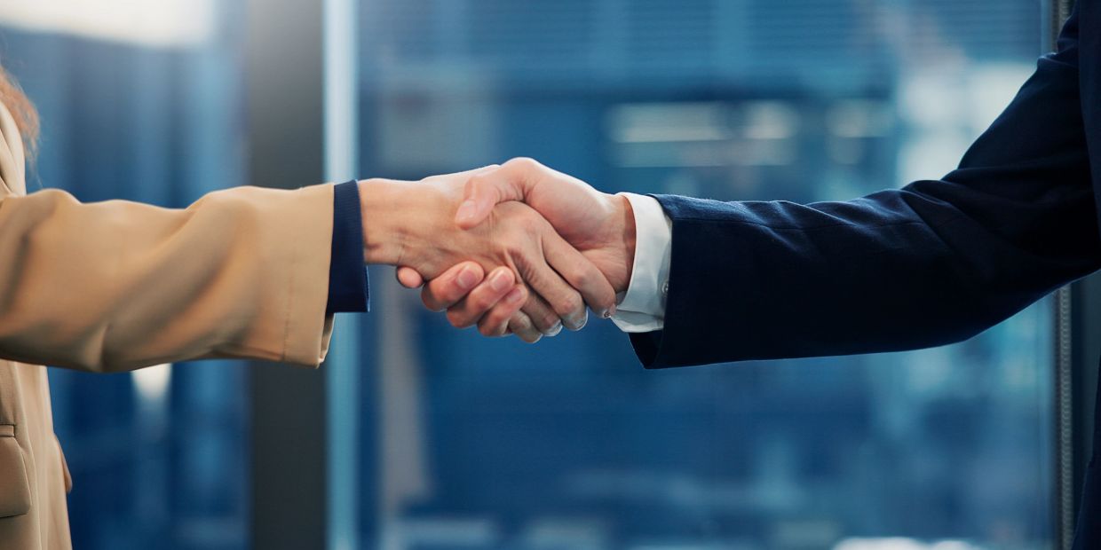 Two people shaking hands in a business setting.Introductory meeting.
