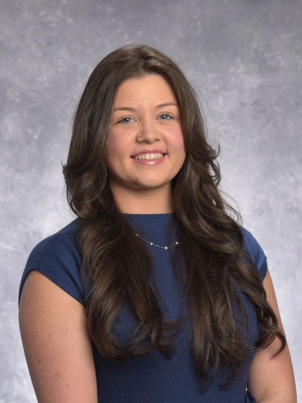 Smiling woman with long brown hair in a blue top.