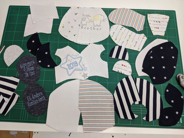 Pieces of a large memory bear cut out from baby clothes on a cutting table